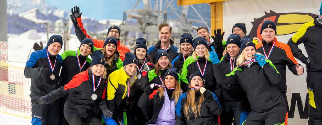 Team in bunter Winterkleidung feiert gemeinsam auf einem Siegerpodest bei einem Teambuilding-Event – professionelle Eventfotografie von Yourfilms.