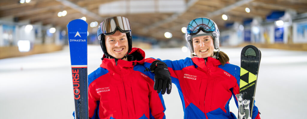 Zwei Skilehrer in roter Skikleidung posieren in einer Skihalle – professionelle Imagefotografie von Yourfilms.